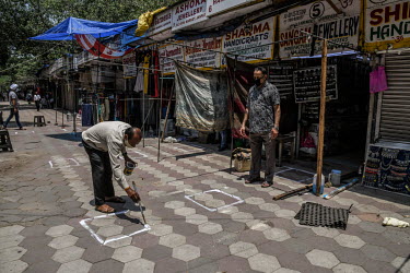 A shopkeeper paints squares on the ground to help people keep to social distancing rules prior to the re-opening of shops following the relaxation of the COVID-19 lockdown as infections across the cou...