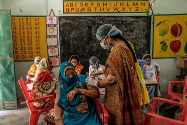A health worker inoculates a woman with a dose of Covishield (AstraZeneca), a COVID-19 vaccine, at a health centre in Mohammadpur Kadeen village.
