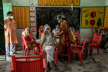 A health worker inoculates a man with a dose of Covishield (AstraZeneca), a COVID-19 vaccine, at a health centre in Mohammadpur Kadeen village.