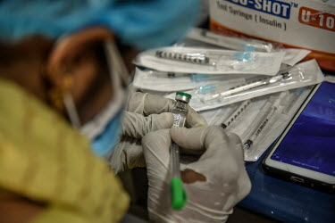 A health worker writes information on a vial of Covishield (AstraZeneca), a COVID-19 vaccine, at a health centre in the city.