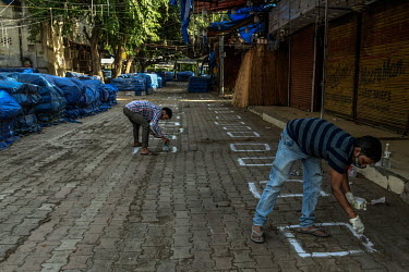 Workers paint squares on the ground to help people keep to social distancing rules at the Nagar market prior to its re-opening following the relaxation of the COVID-19 lockdown.