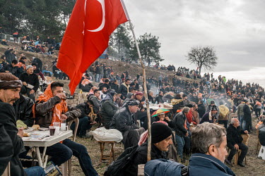 Spectators drinking Raki sit by a Turkish flag while watching the 35th annual Selcuk Camel Wrestling Festival competition near Izmir.