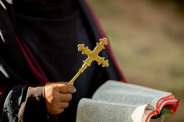 A priest holds a cross and bible in Qusquam, Gondar.