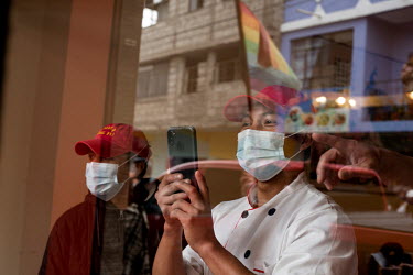 Restaurant staff take photos of the 'National March for Democracy' as it arrives in Cotopaxi.