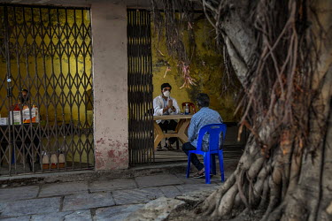 A young volunteer doctor, Robin Lohia, consults a patient with suspected COVID-19 symptoms at a community centre, under a Banyan tree at Ghitorni village, temporarily being used as an outpatient depar...