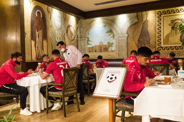 Players from the Afghanistan national football team eating a meal at their training base hotel.