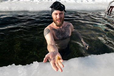 Egor Lesnoy, a blogger and activist from Irkutsk holds an insect larva as he swims in a pool cut through the frozen surface of Lake Baikal. He took a great interest in diving and scuba diving in the l...