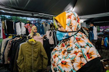 A shoper browsing. Muhammad Mat Nor the owner of Mad X Station bundle shop and his wife sorts out clothes in the background. He says business has been much slower since the pandemic. People in Malaysi...