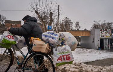 An elderly man carries bags full of plastic bottles he has collected to take by bike to a recycling collection point.
