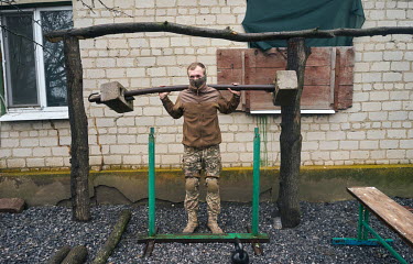 A military intelligence soldier, some 5kms from the frontlines, lifts an a makeshift gym weight. The soldiers have built a makeshift gym to use when they're not in the trenches.