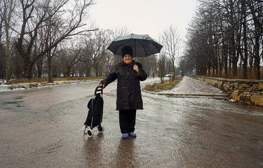 Yelena (67) shelters from rain beneath an umbrella. The war in Ukraine divided families and friends. Yelena says she has two sons, one is pro-Russian and the other pro-Ukrainian. The brothers don't ta...