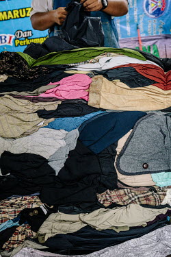 Muhammad Mat Nor the owner of Mad X Station bundle shop sorting out clothes he unpacks from bales. He says business has been much slower since the pandemic. People in Malaysia use the term 'bundle' fo...