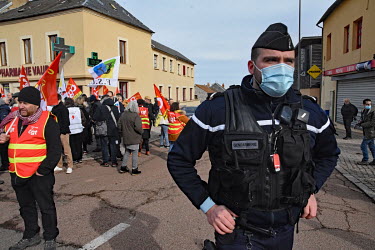 A gendarme monitors trade unionists and left wing activists at a counter demonstration during a rally for far right presidential candidate Eric Zemmour.