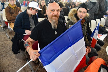 A supporter of far right presidential candidate Eric Zemmour who has a tattoo of the confederate flag, holds the French national flag at a rally in Burgundy.