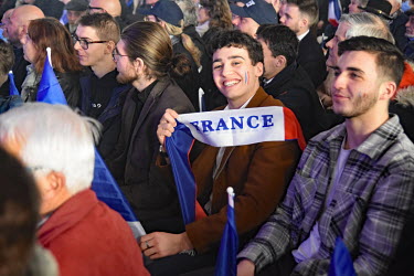 A supporter of far right presidential candidate Eric Zemmour smiles and holds a sash of the French national flag at a rally in Burgundy.