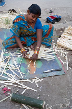 A woman making baskets from bamboo offcuts.