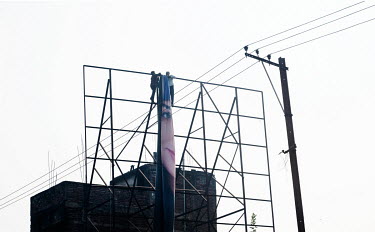 Workers erect a billboard advertising face cream.