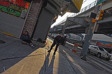 A man lies propped up outside a pawn shop while another man staggers along the pavement on Kensington Avenue in North Philadelphia, between Huntingdon and Allegheny on the elevated Market-Frankford su...