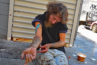 A drug users injecting himself on the street in North Philadelphia, between Huntingdon and Allegheny on the elevated Market-Frankford subway. This is the epicentre of the city's opioid (fentanyl) drug...