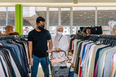 Malay family shopping at Family Bundle, a thrift shop selling second hand clothes. People in Malaysia use the term 'bundle' for secondhand shopping, a reference to the large bales that local clothing...