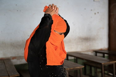 A Muslim woman ties her bright orange niqab.