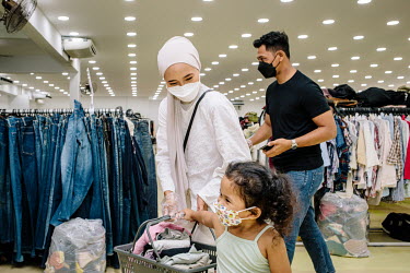 A Malay family shopping at Family Bundle, a thrift shop selling second hand clothes. People in Malaysia use the term 'bundle' for secondhand shopping, a reference to the large bales that local clothin...