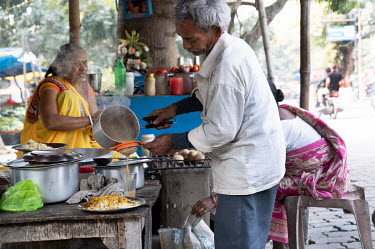 An older couple work at their tea and snack street stall.