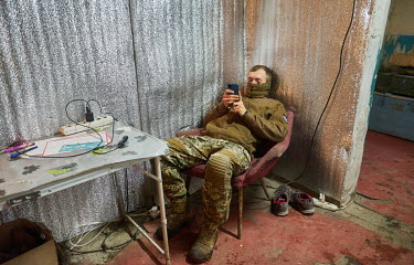A military intelligence soldier checks his mobile phone while resting in a guard post that is about 500 metres away from the positions of the pro-Russian separatists.