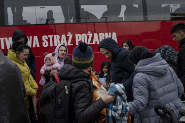 Ukrainian refugee families, fleeing the Russian invasion, alight from buses, arranged by the fire department, that have brought them to Przemysl from the border crossing with Ukraine.