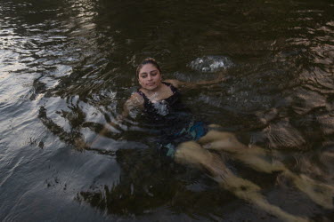 Reyna Herrera (29) swims in a river after work. Reyna was born in Fresno and grew up in Michoacan. She has three children who she leaves with her mother in Mexico while she comes to work in the fields...