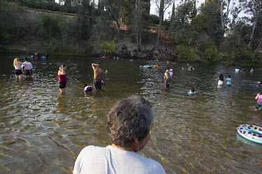 Farm workers wash and play in a river after work.