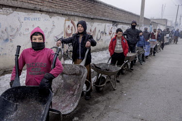 Boys, including Ezatullah Sarware (12) (pink hoodie), stay off school to earn some money by acting as porters, using wheelbarrows to move sacks of food distributed by the World Food Program (WFP) to s...