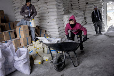Ezatullah Sarware (12) (pink hoodie), stay off school to earn some money by acting as a porter, using a wheelbarrow to move sacks of food distributed by the World Food Program (WFP) to starving Afghan...