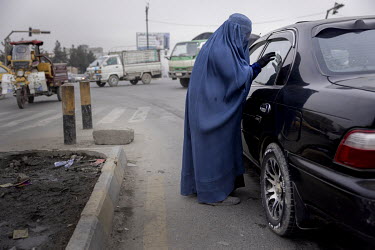 Fatema, begs for money or food from a passing car in the city centre.