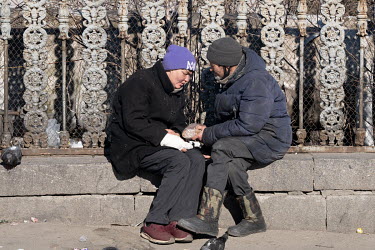 A man hands a loaf of bread to a homeless woman.