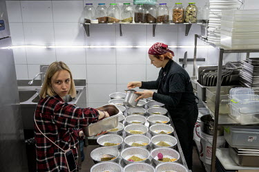 Volunteers fill disposable foil dishes with spicy south east Asian foods that are rich in protein and carbohydrate at the Food vs Marketing army meals project.