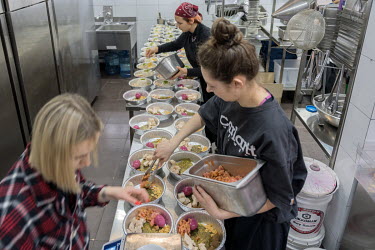 Volunteers fill disposable foil dishes with spicy south east Asian foods that are rich in protein and carbohydrate at the Food vs Marketing army meals project.