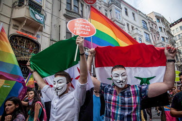 Syrian participants at Istanbul Pride hold both government and opposition flags, with the rainbow flag symbolising the LGBT community's pride and fight for equality in society.
