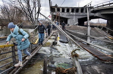 Residents of the suburb of Irpin in west Kyiv, negotiate a river via the remnants of a bridge that was destroyed several days earlier to impede the Russian advance, as they try to leave the area after...