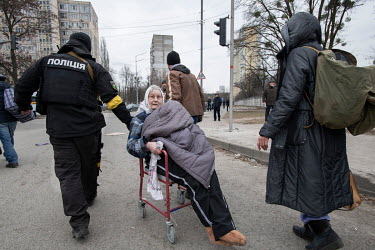 A policeman helps an elderly woman in a wheelchair as residents of Irpin evacuate to Kiev (Kyiv) from the suburb that has been heavily bombed by invading Russian forces.