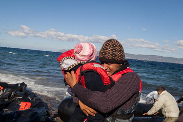 A father and holds his child as they arrive in Europe via a boat from Turkey.