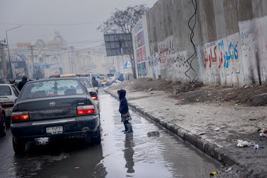 A child begging for money or food from people in a car stuck in traffic in central Kabul.