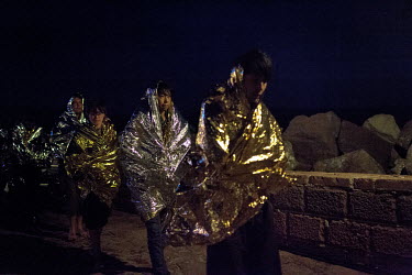Afghan asylum seekers walk along the port in Molyvos after being rescued by the Hellenic Coastguard during a crossing from Turkey.