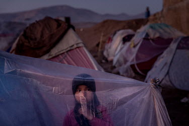 A child sits in a makeshift tarpaulin tent in a camp where about one thousand people have moved from their villages and farms in the countryside due to the food-crisis, and are now living in subhuman...