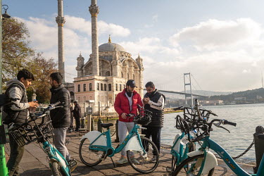 Foreign tourists with rental bicycles in front of the Ortakoy Mosque, with Istanbul's Asian shore in the background, during a nationwide weekend coronavirus curfew which didn't appear to apply to over...