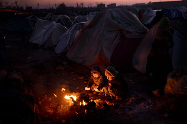 Two children boil water for tea on a fire in a camp where about one thousand people have moved from their villages and farms in the countryside due to the food-crisis, and are now living in subhuman c...