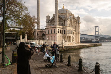 Foreign tourists take photos in front of the Ortakoy Mosque, with Istanbul's Asian shore in the background, during a nationwide weekend coronavirus curfew which didn't appear to apply to overseas visi...