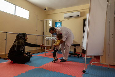 A physiotherapist works with a 2-year-old cerebral palsy patient, Sidra, and her mother at the city hospital.