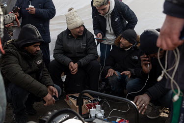 A group of Pakistani men charge their phones after crossing from Ukraine to Poland, fleeing the Russian invasion.