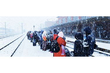 Ukrainian refugees waiting in the snow on a platform at Suceava's station for a train to take them directly to Bucharest.